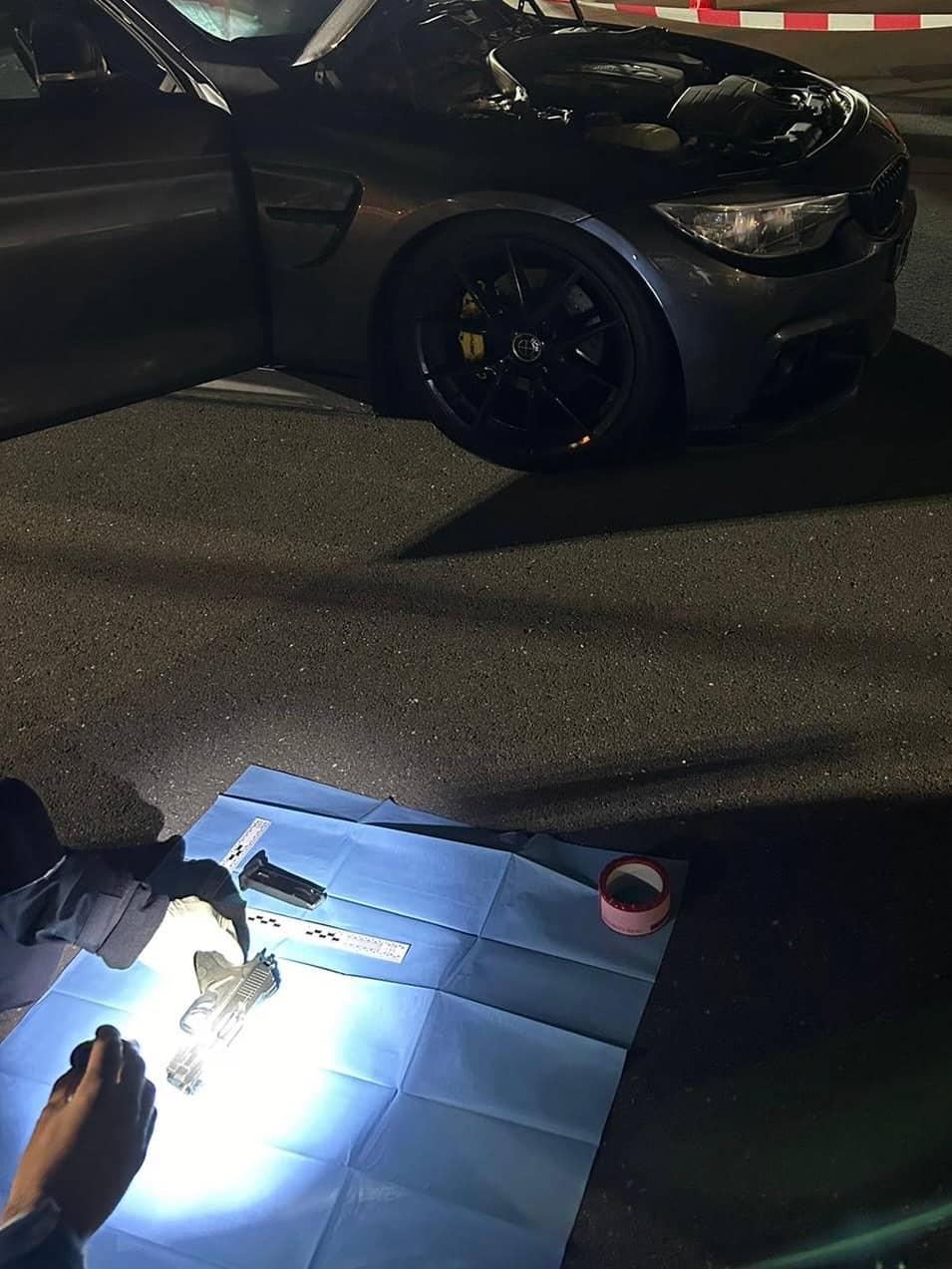 Forensische Opsporing van de Marechaussee onderzoekt wapen naast het voertuig